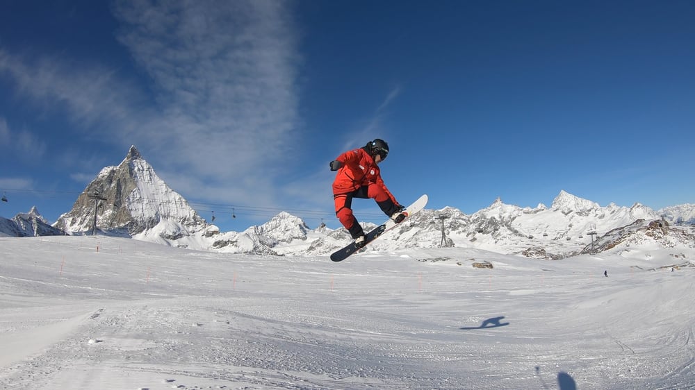 A snowboarder in red carving down a Zermatt slope