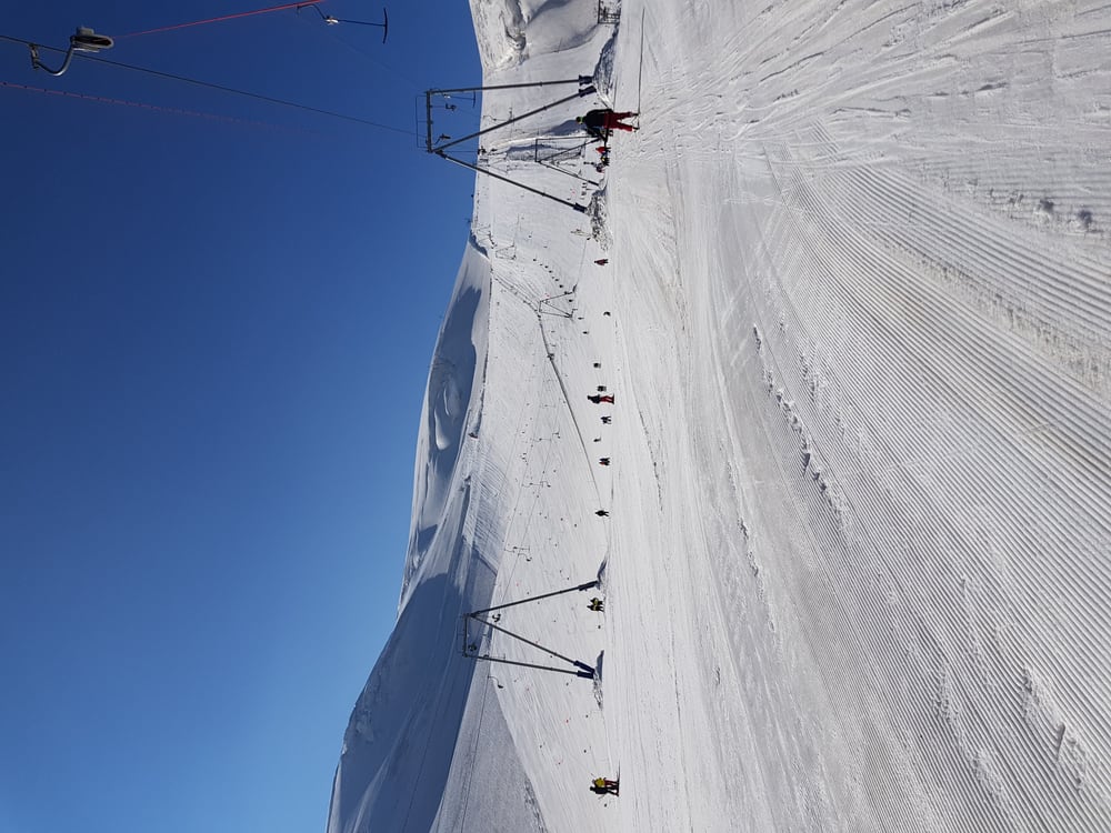 A groomed summer ski slope on the glacier under a clear sky